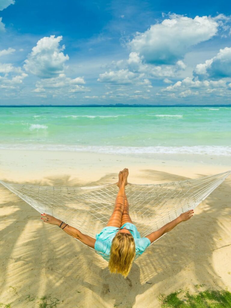 A woman relaxing in a hammock on a tropical beach, enjoying her travels.