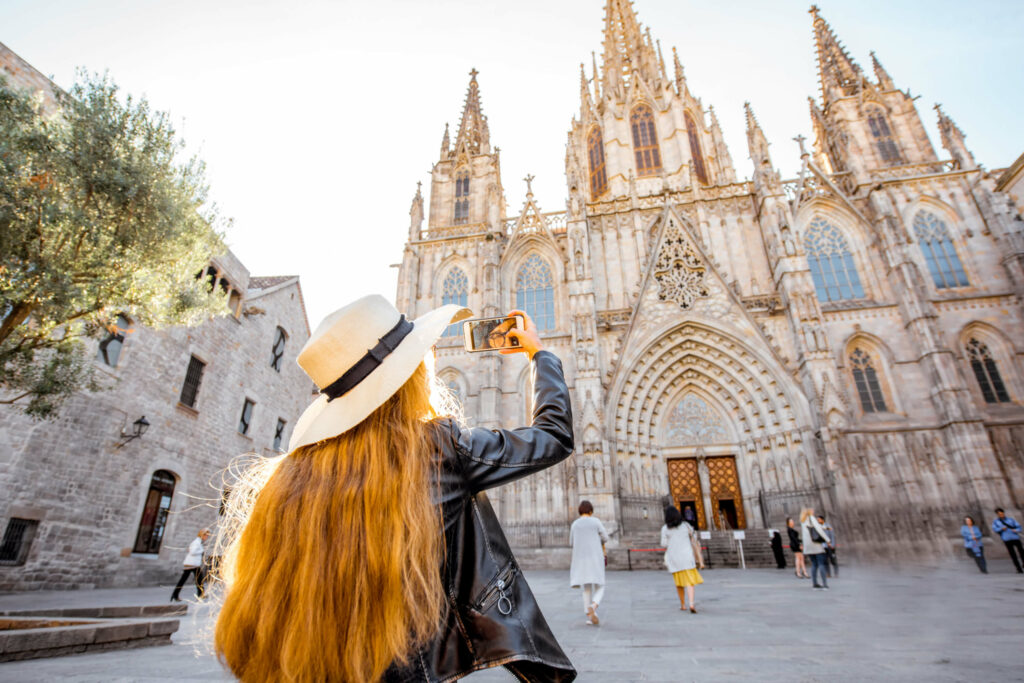 Picture of a woman taking a photo of a cathedral during a stop on a Barcelona tapas and wine tasting walking tour.