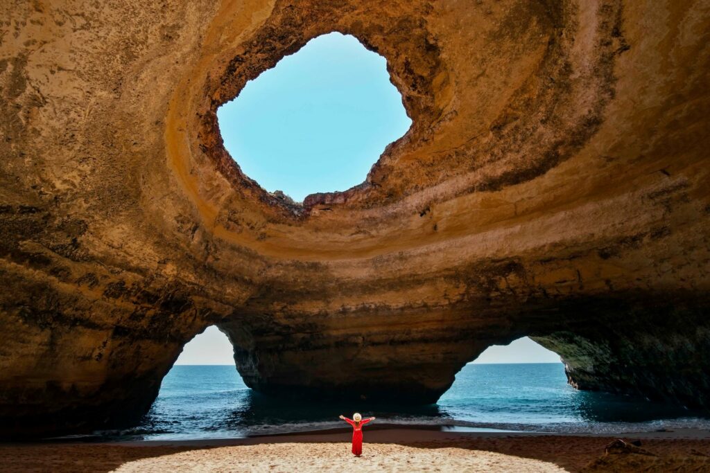 A photograph taken inside the amazing caves at Benagil in Portimao, Portugal, showing the sky and the sea through the cave openings.