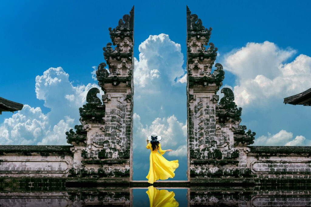 Picture of a woman in a yellow dress and a white standing at a the opening of a temple in Ubud, Batuan during a tour in Bali.