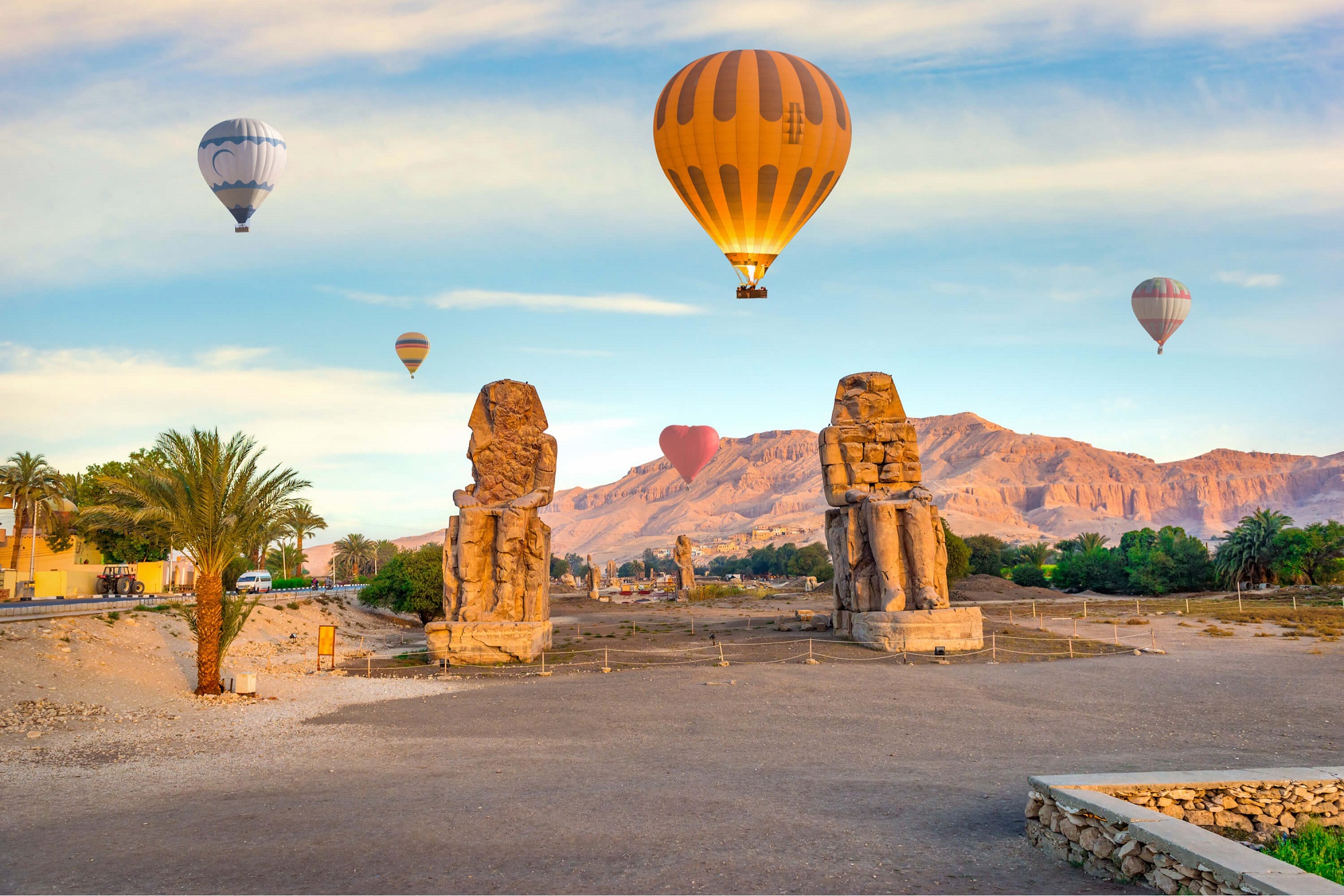 Travelers can witness hot air balloons drifting over ancient Egyptian ruins in the beautiful landscape below.