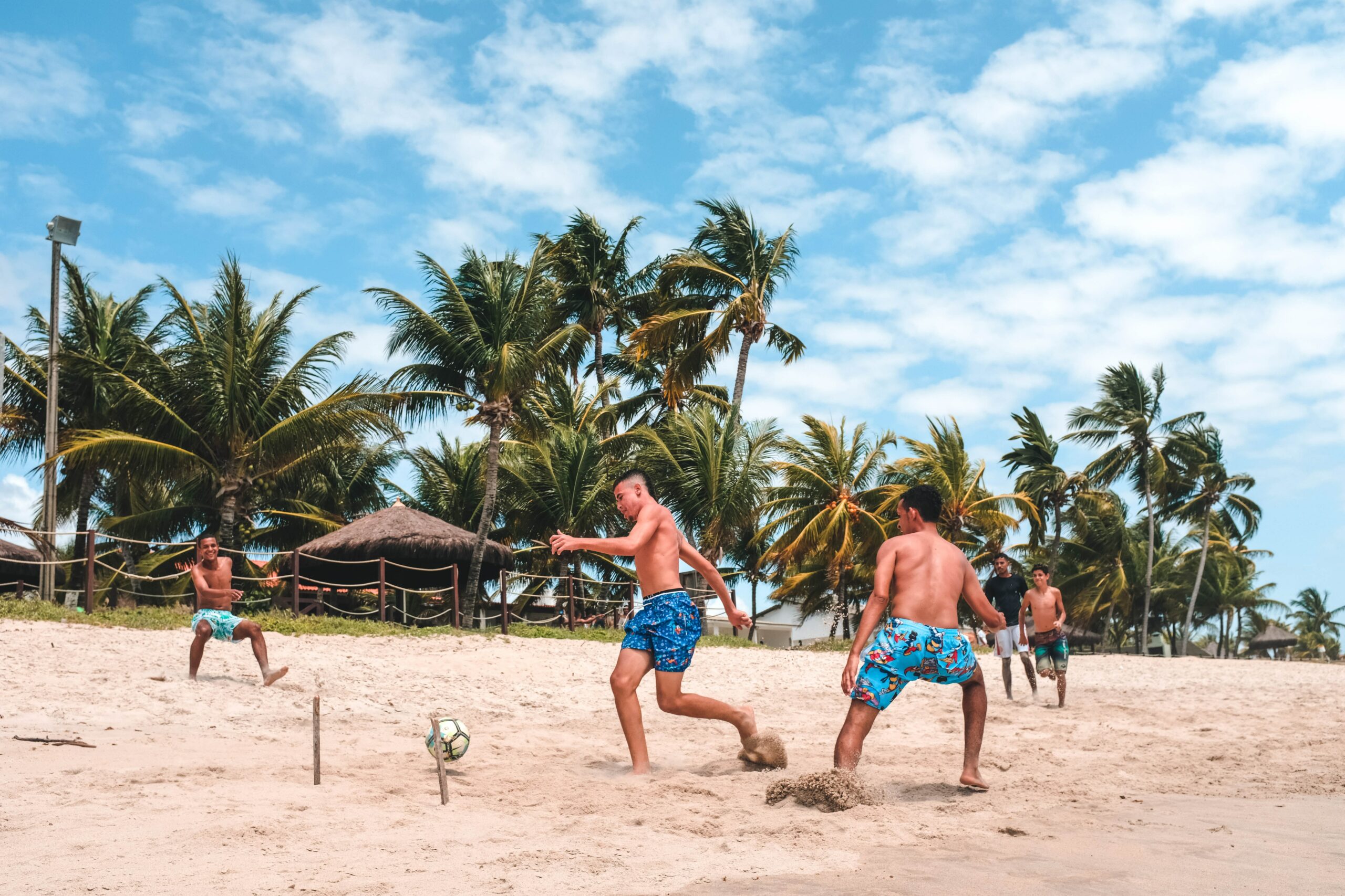 A group of men playing frisbee on the beach.