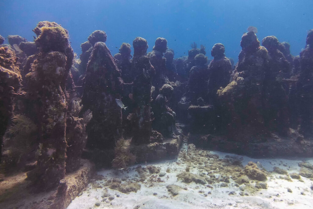 An underwater photo of submerged art at the MUSA underwater museum in Cancun, Mexico.