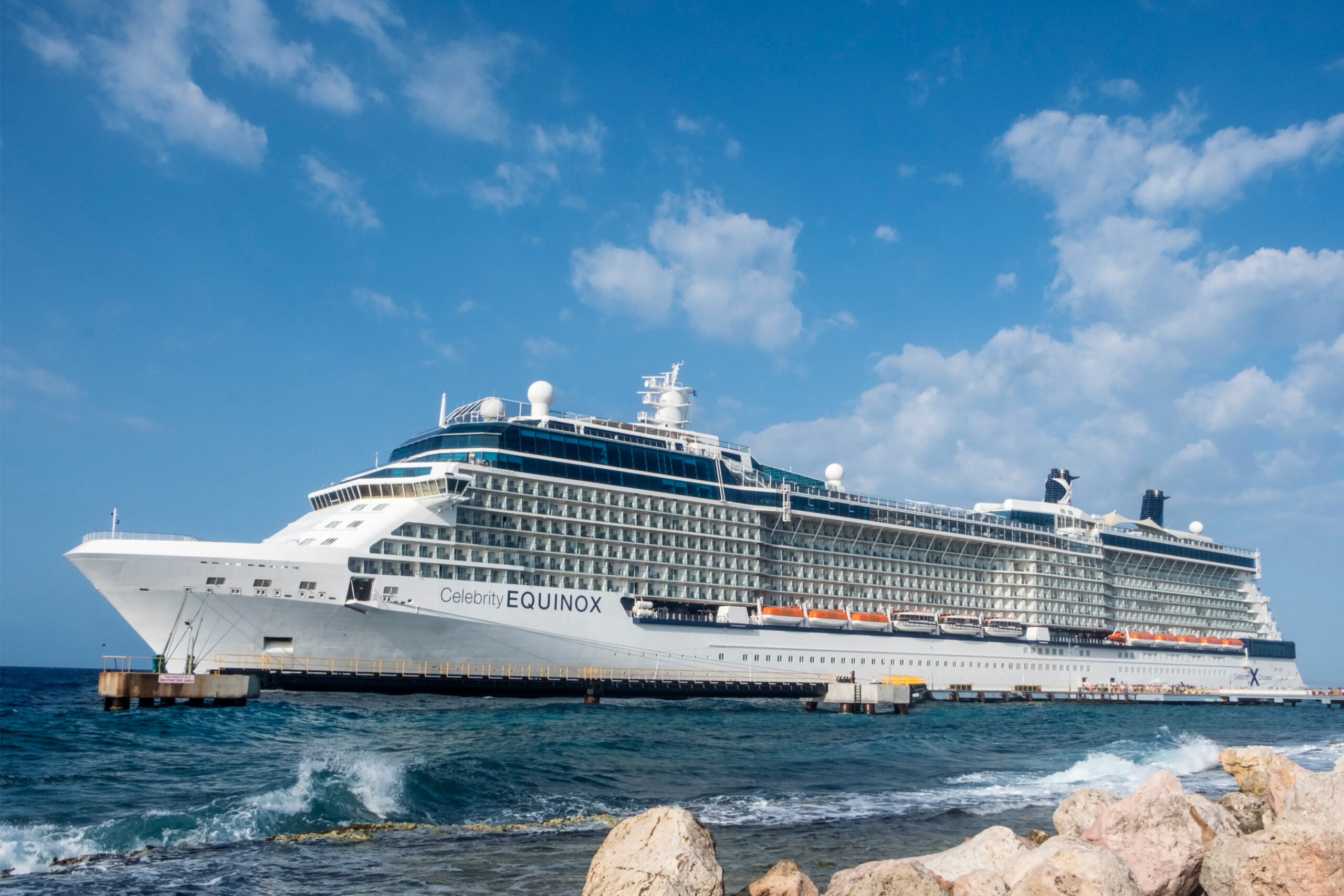 A large cruise ship docked at the rocky shore during a holiday.