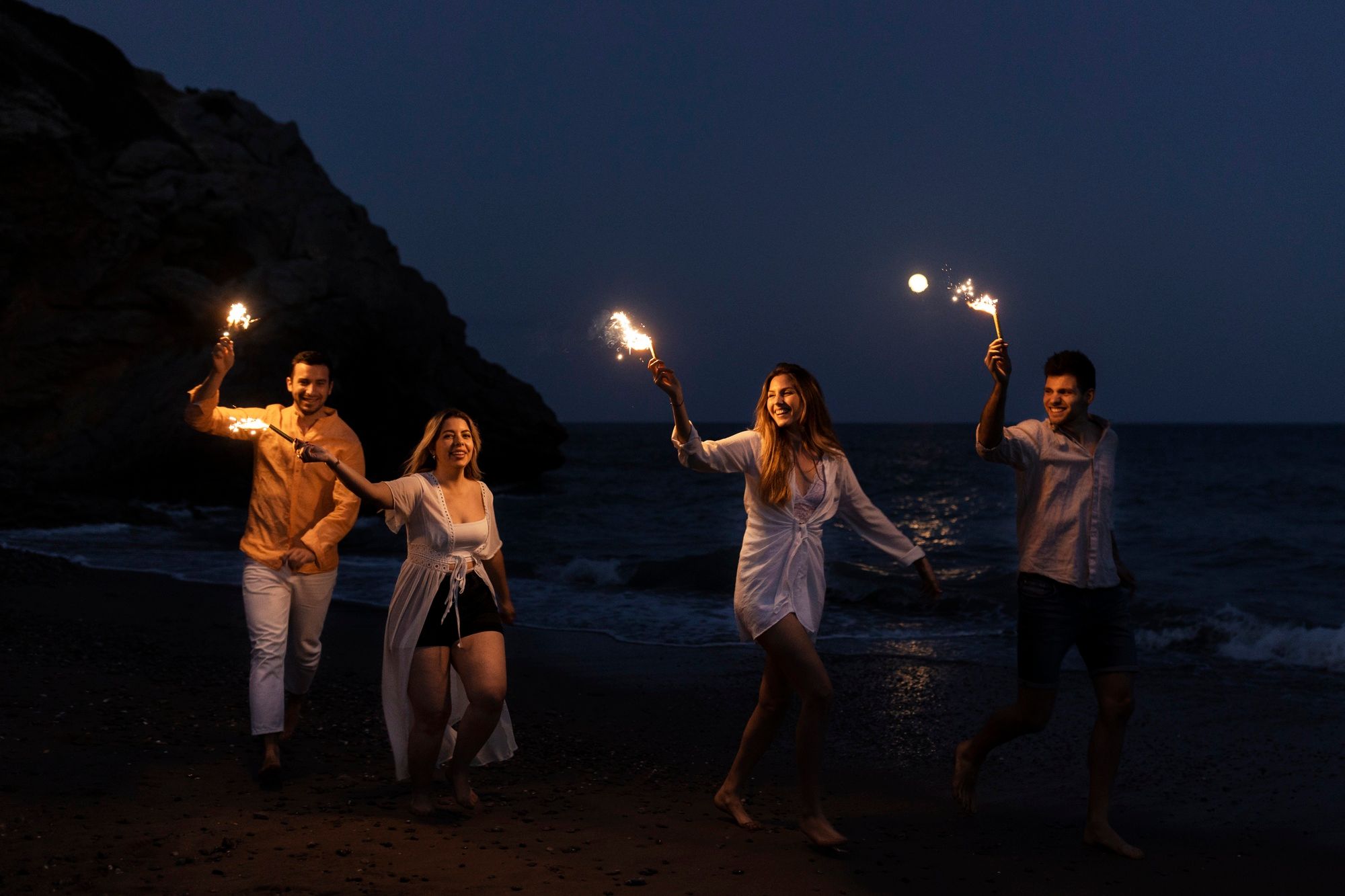 friends having fun holding torches at the beach during nightime.