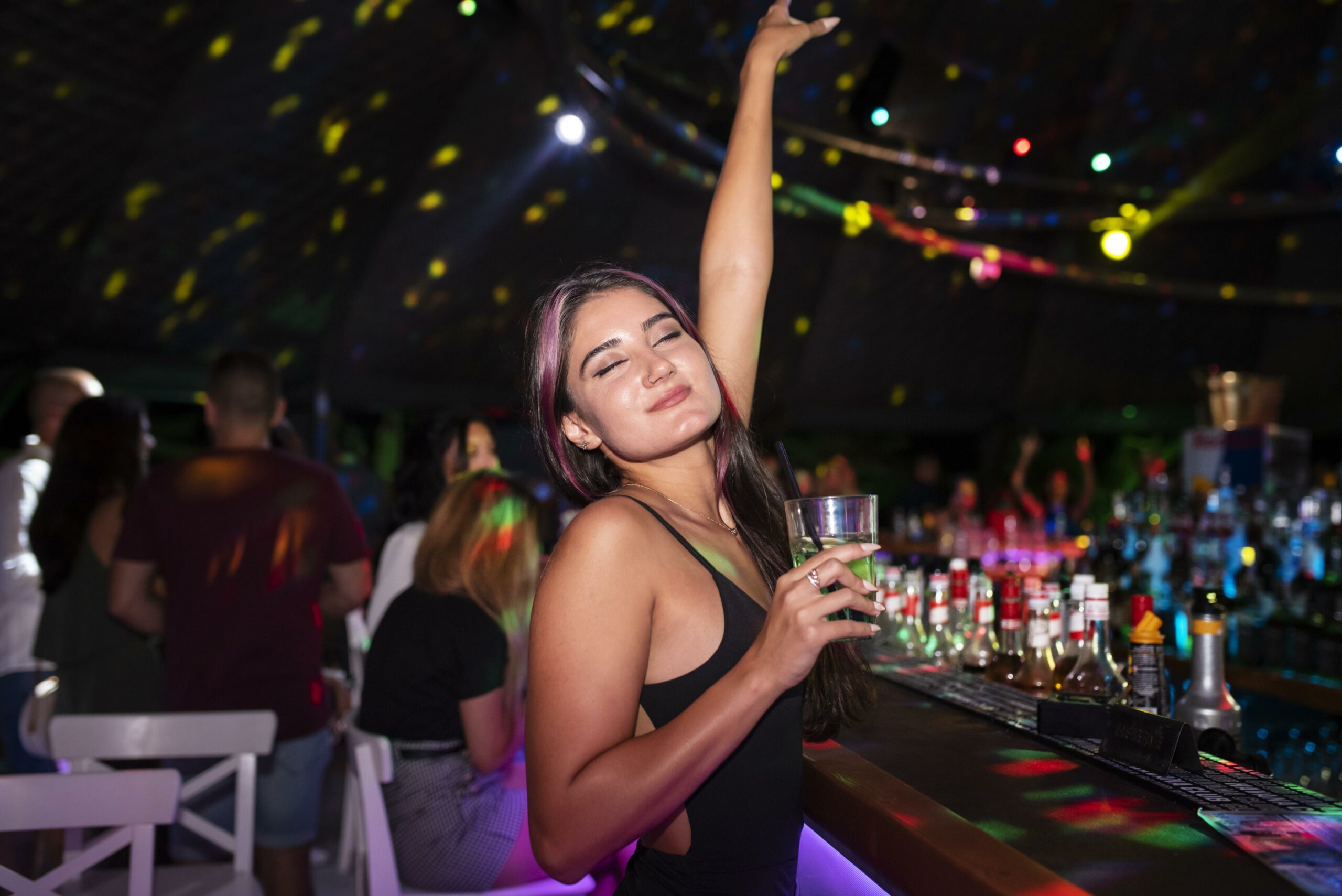 Girl smiling and enjoying a cocktail at an outdoor bar in cancun , nightime