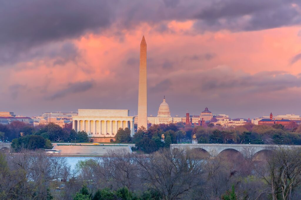 Photo of the Washington Monument with a red sky and the Capitol building in the background.