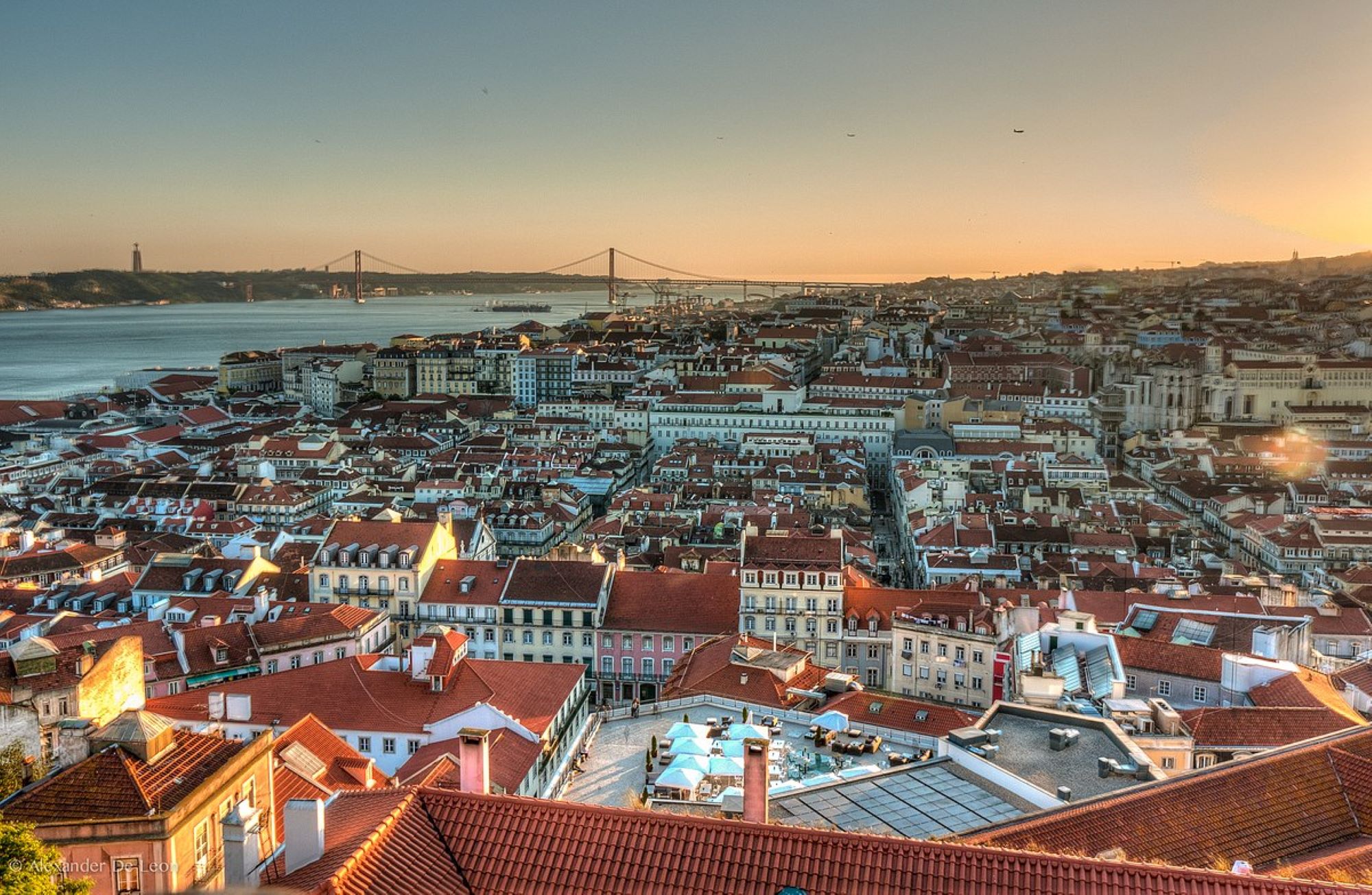 Sunset over river tagua and red bridge in Lisboa, city seen from above, red tiles rooftops and typical houses.