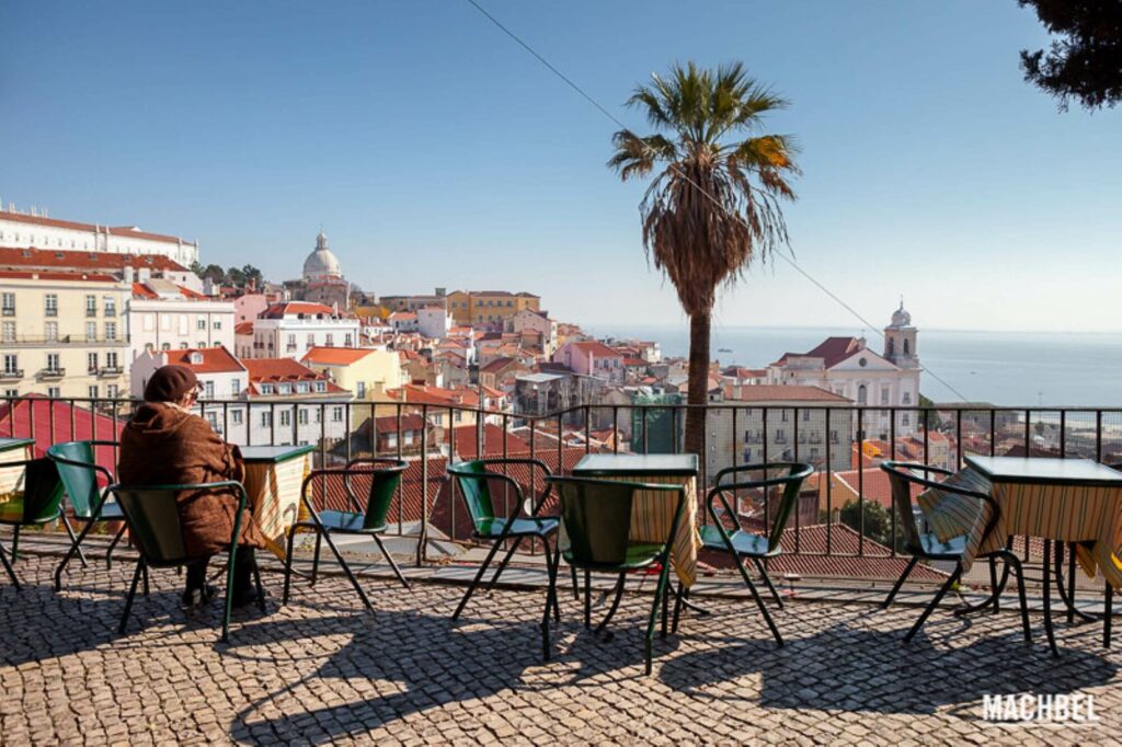 overview to Lisboa's rooftops, monuments, castle and river, tables and chairs